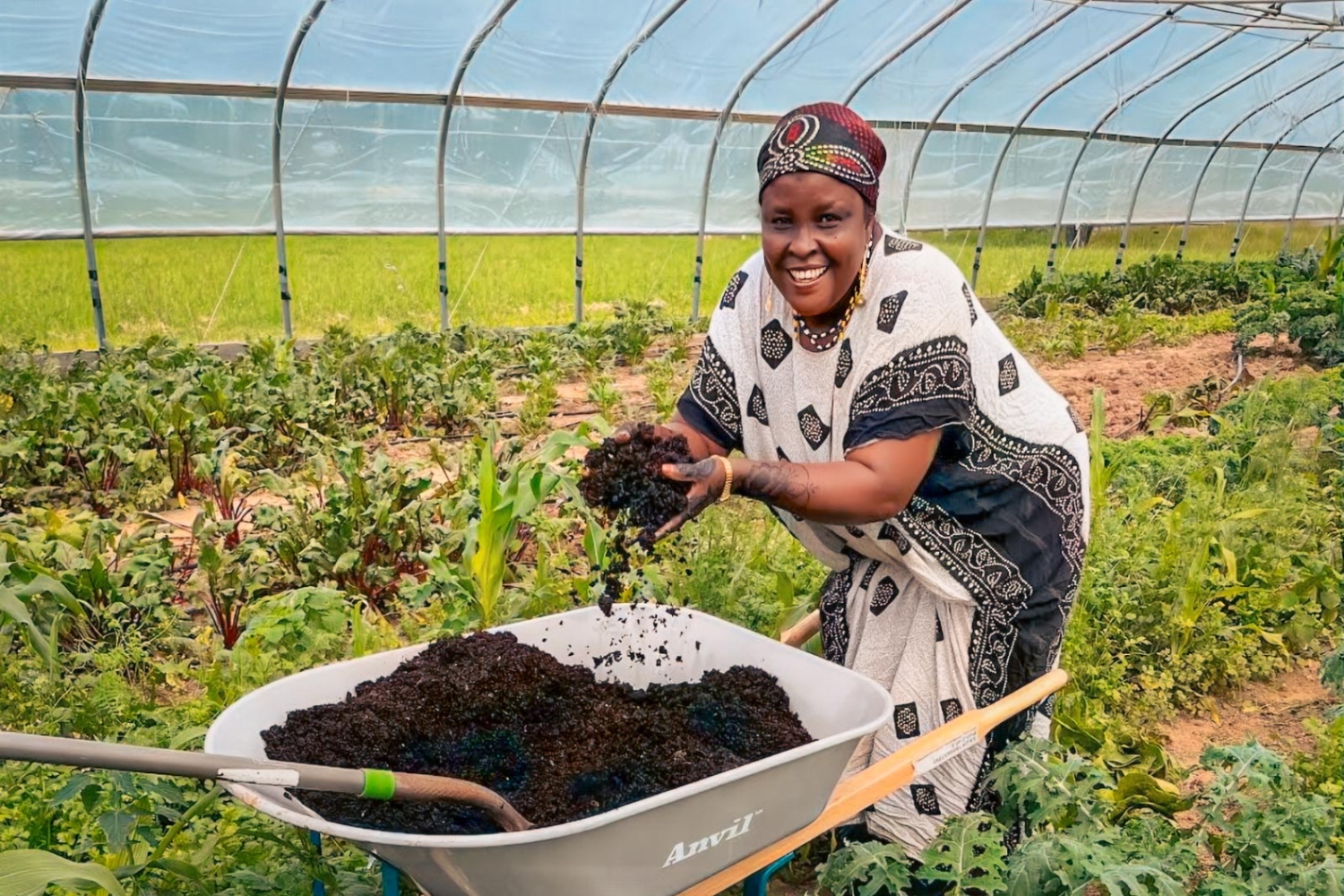 Smiling Somali Bantu woman prepares compost in lush greenhouse garden 1500x1000 1